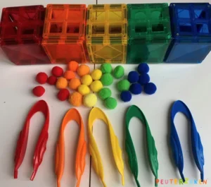 Bakjes van magnetische tegels met gekleurde pompoms en een pincet